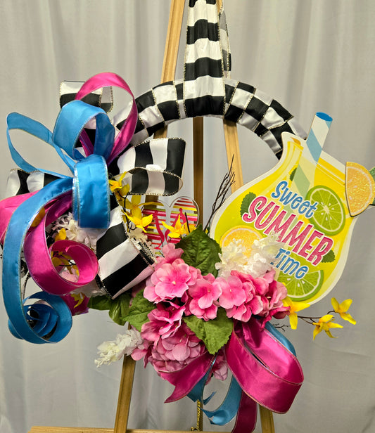 14″ summer wreath with bright blue, hot pink & yellow mesh, pink florals, flip-flops, ribbon accents, and a glass of lemonade