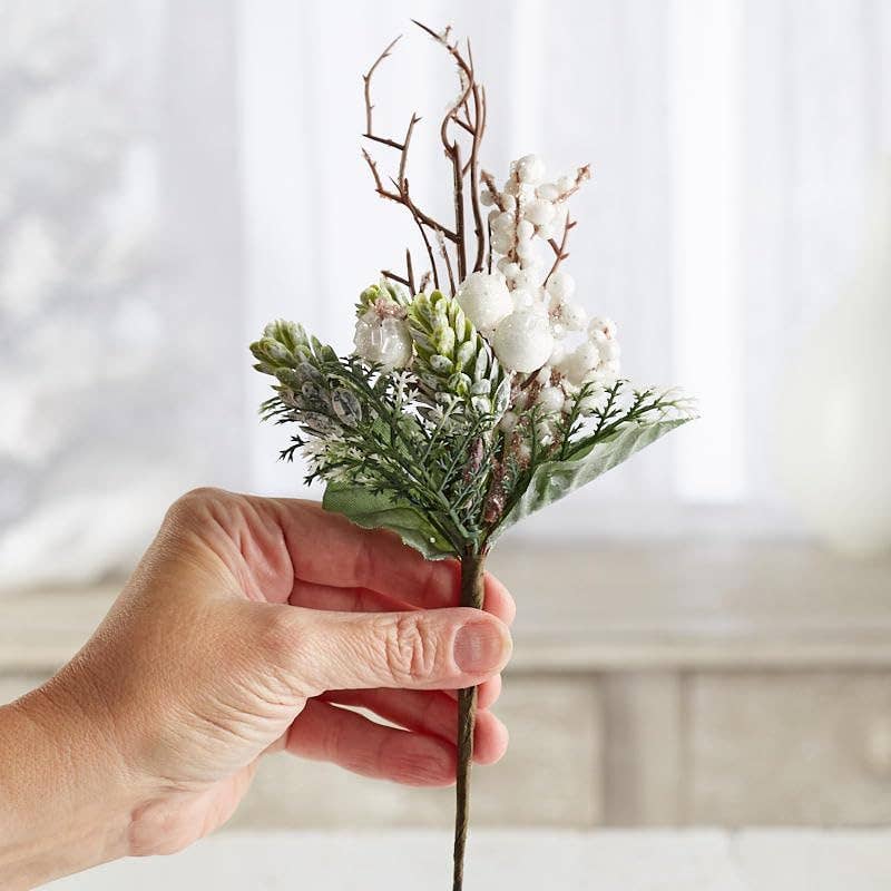 Close-up view of frosted winter berry pick showing artificial snow glitter coating on berries leaves and cedar branches