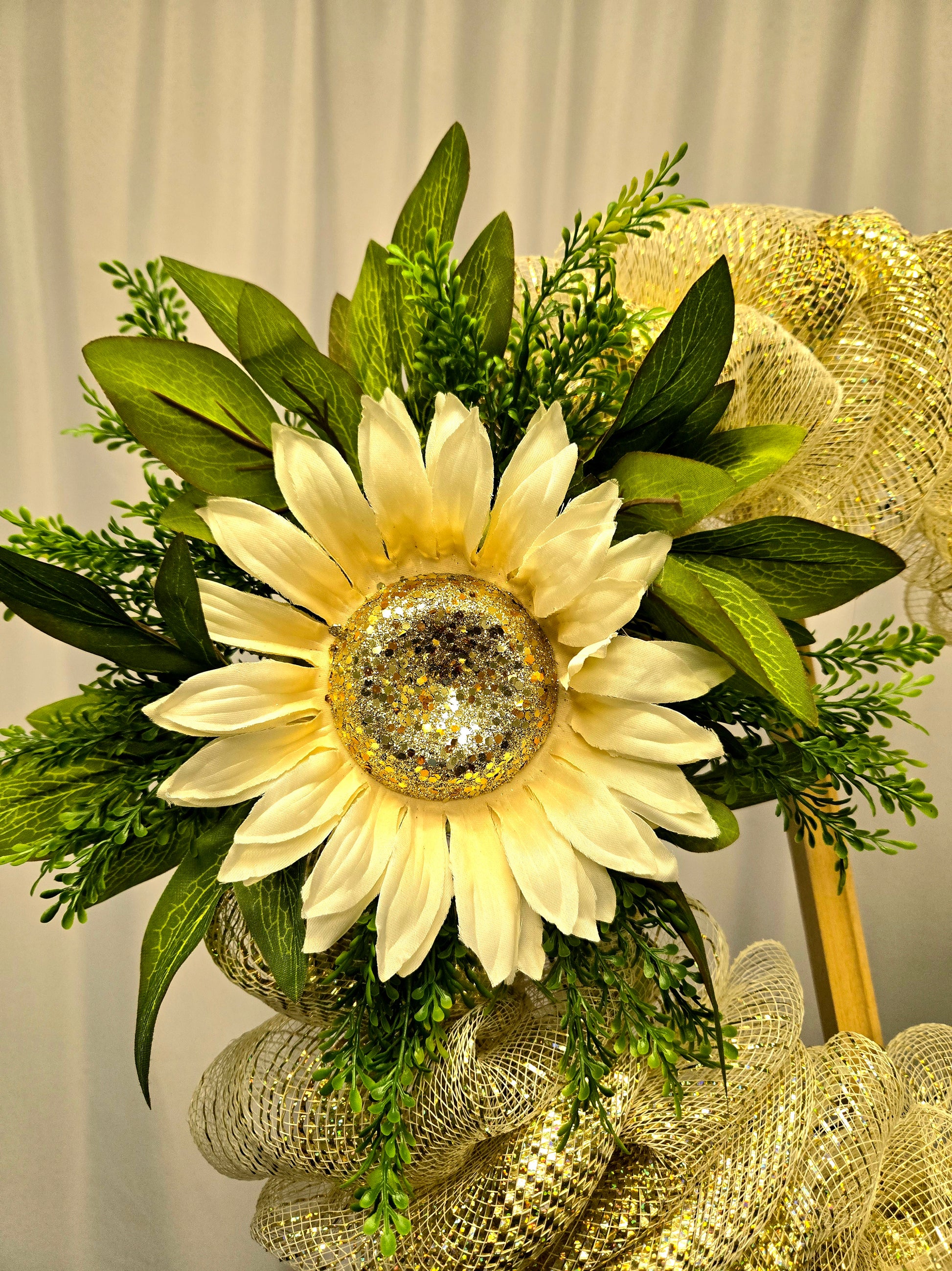 14″ wreath featuring a large cream and gold sunflower on a gold mesh base with greenery
