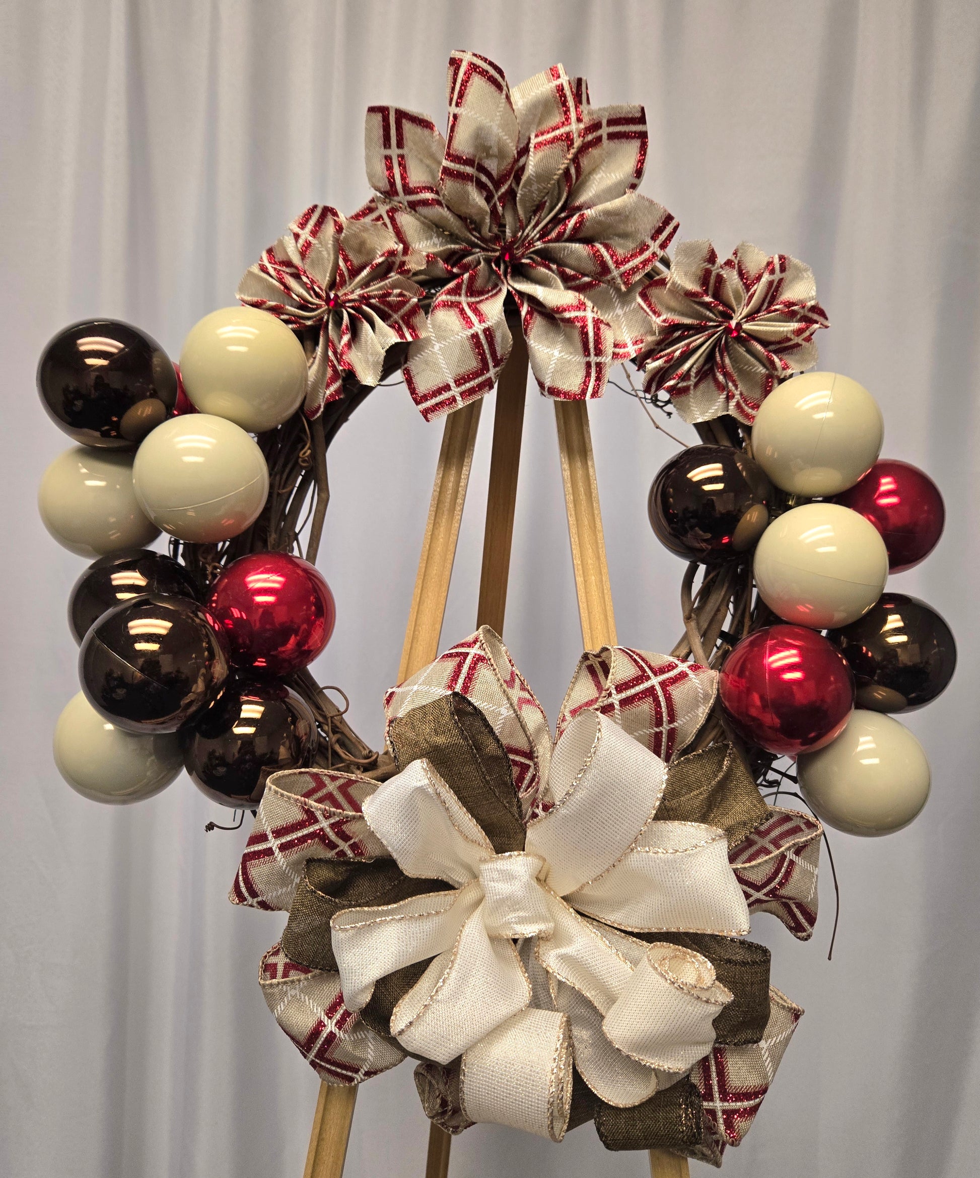 12″ Designer’s Choice holiday wreath with brown, red, and beige ornaments, poinsettia ribbon flowers, and multi-ribbon bow

