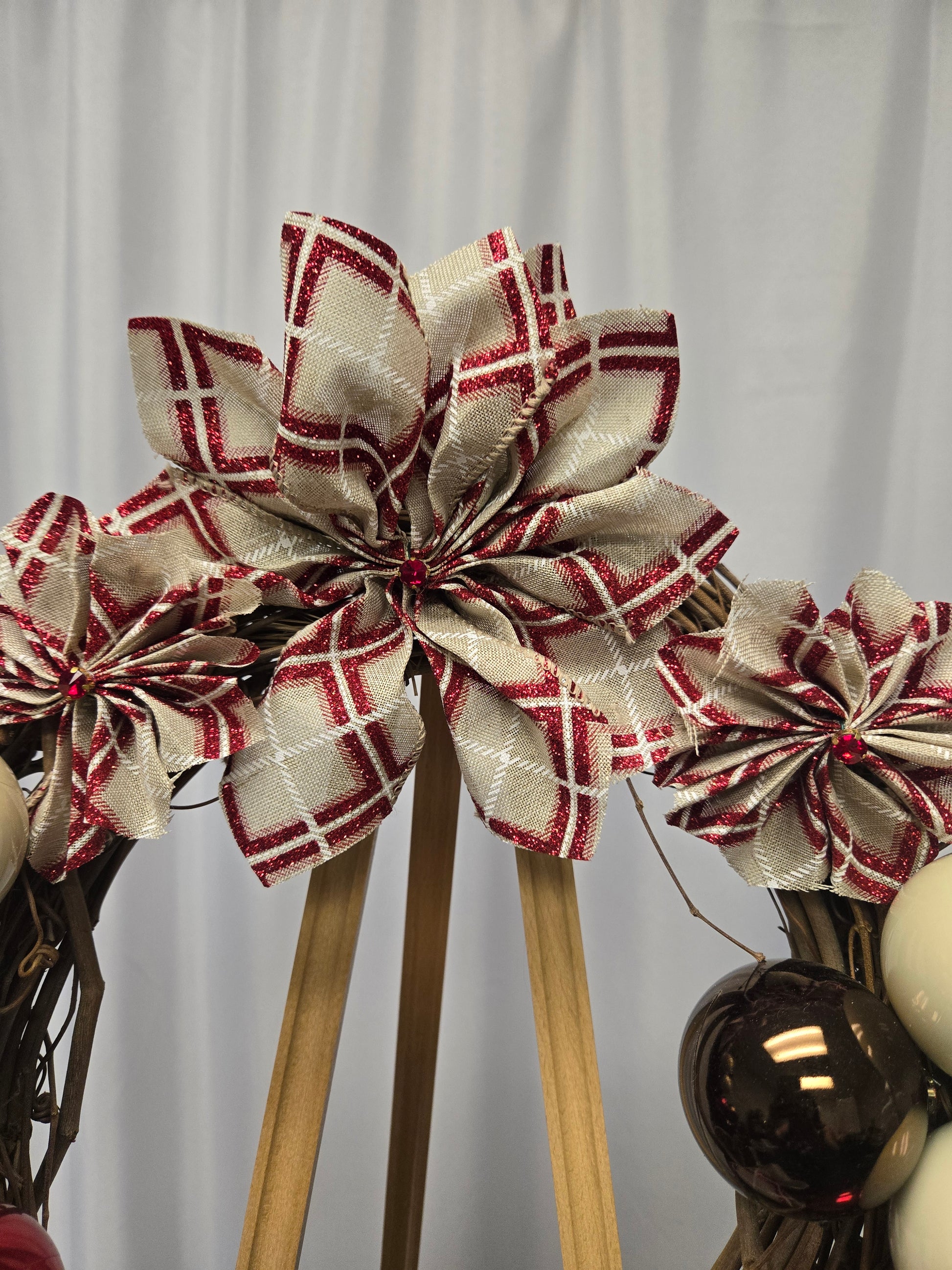 12″ Designer’s Choice holiday wreath with brown, red, and beige ornaments, poinsettia ribbon flowers, and multi-ribbon bow
