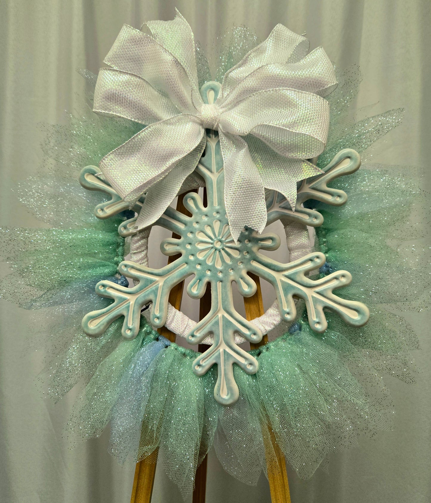 8″ wire wreath with teal and white metal snowflake, pale blue and teal mesh ribbons, and iridescent white bow
