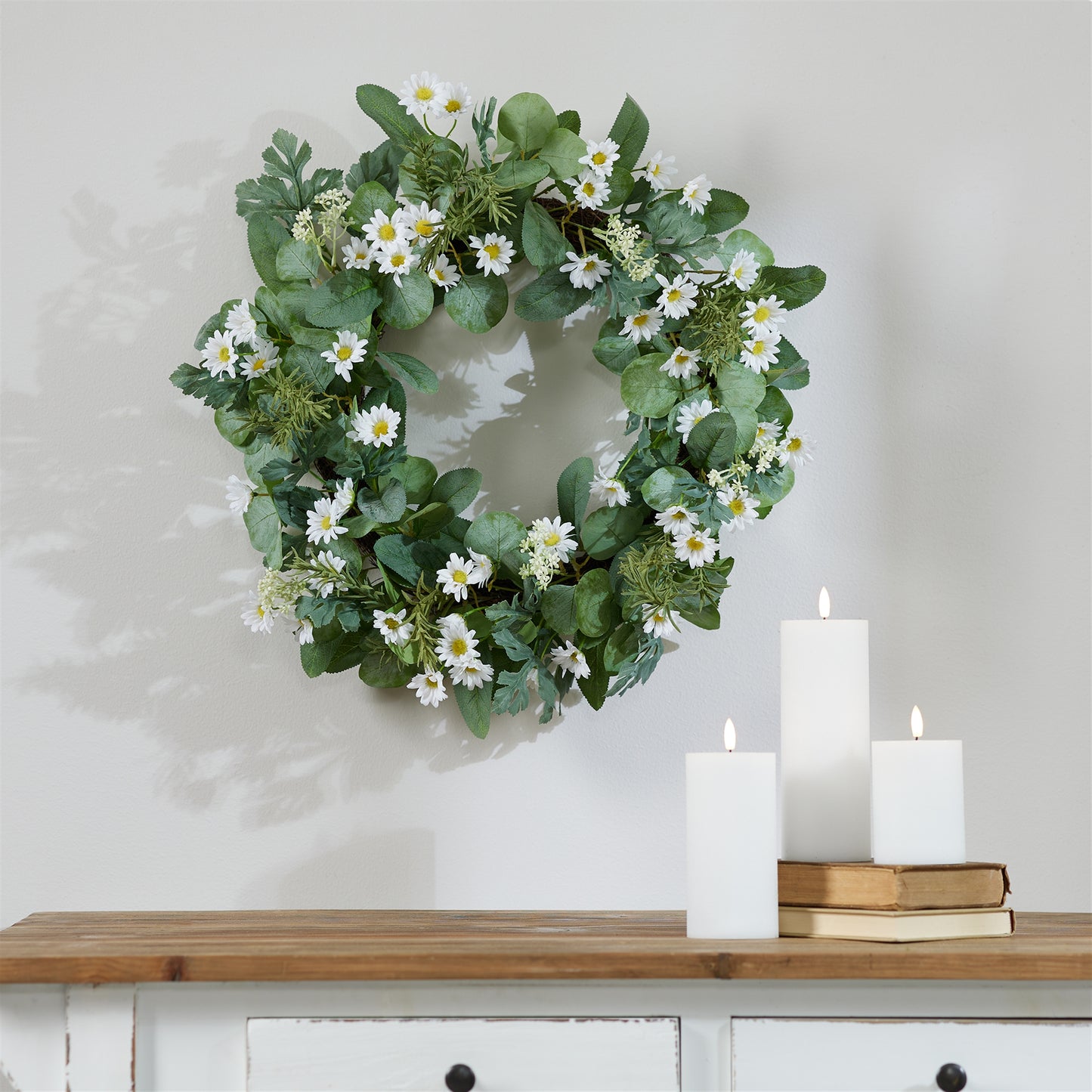 Spring floral wreath with green foliage hanging on wall